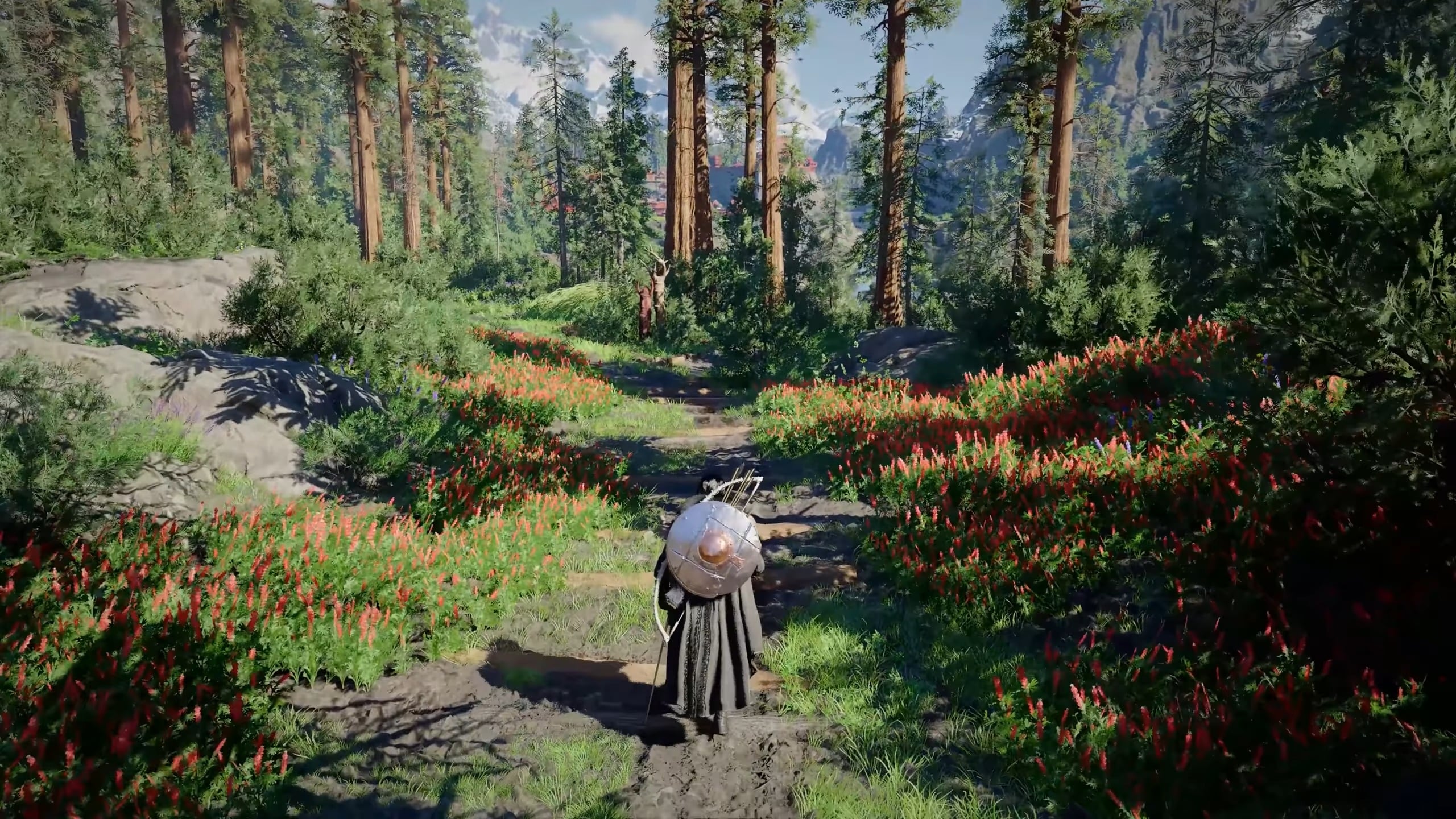 Vue de dos d'un personnage portant un bouclier rond et un carquois avec un arc, marchant sur un sentier forestier. Le chemin est bordé de buissons verts et de parterres de fleurs rouges vives. En arrière-plan, on distingue de grands arbres élancés et des montagnes enneigées sous un ciel clair.